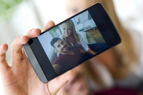 Beautiful young couple using mobile phone at home. — Stock Photo, Image