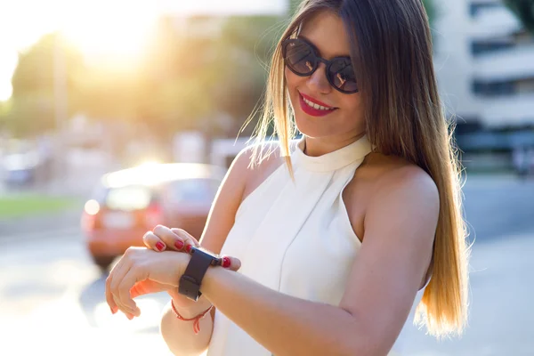 Mooie jonge vrouw met haar smartwatch in de straat. — Stockfoto