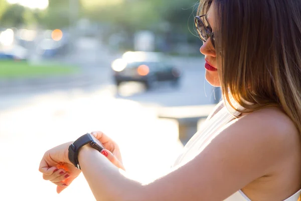 Mooie jonge vrouw met haar smartwatch in de straat. — Stockfoto