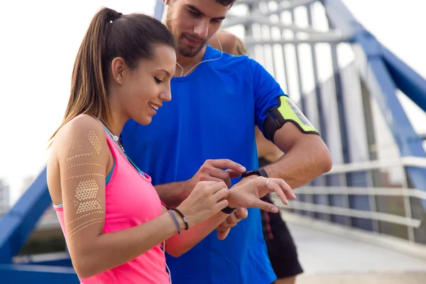 Odkryty młoda para przy użyciu ich pokładzie smartwatch po uruchomieniu. — Zdjęcie stockowe