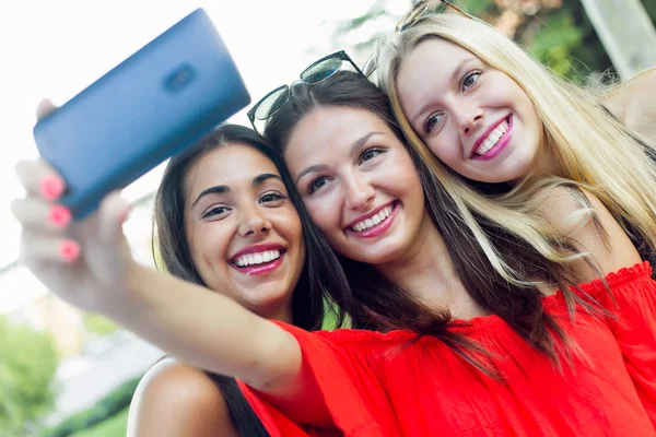 Três amigos tirando fotos com um smartphone na rua . — Fotografia de Stock