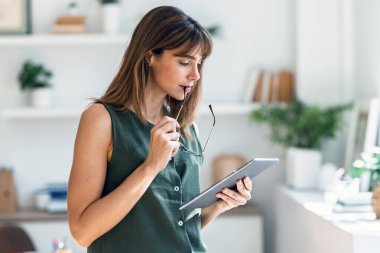 Modern bir ofiste çalışırken dijital tabletini kullanan bir kadın resmi..