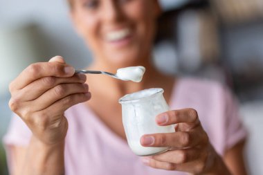 Evdeki kameraya bakarken yoğurt yiyen mutlu kadına yaklaş.