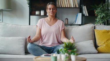 Evdeki kanepede yoga yapan rahatlatıcı kadının videosu.