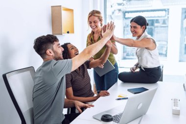 Bir grup başarılı zeki iş adamının iyi bir iş çıkarmasını kutlarken birlikte çalıştıkları yerde sağ kollarını kaldırmaları..