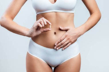 Karnında hap olan yakın plan genç bir kadın. Mavi kara zeminde izole edilmiş.