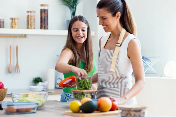 Güzel bir anne ve kızının mutfakta konuşurken birlikte sağlıklı yemekler pişirmesi.