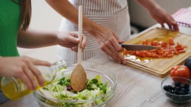 Güzel anne ve kızının mutfakta konuşurken birlikte sağlıklı yemek pişirdikleri video.