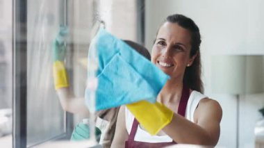 Neşeli anne ve kızın evdeki mutfak pencerelerini temizlerken çekilmiş bir video.