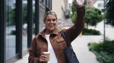 Dost canlısı bir kadının şehirde yürürken birine el salladığı bir video.