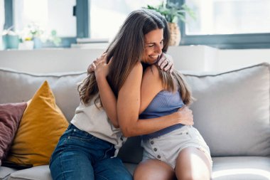 Güzel bir anne ve kızın evdeki kanepede otururken şefkatle kucaklaşması.