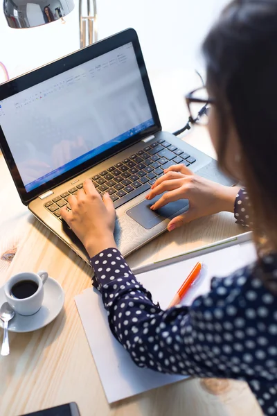 Vacker ung kvinna som arbetar med laptop-kontoret. — Stockfoto