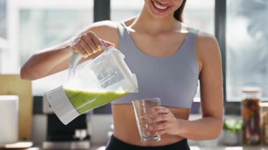 Evdeki mutfakta sebze yeşili smoothie servis eden genç bir kadının videosu..