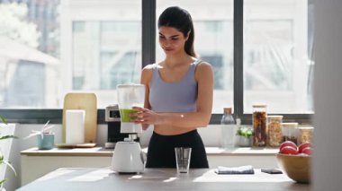 Evdeki mutfakta sebze yeşili smoothie yapan genç bir kadının videosu..