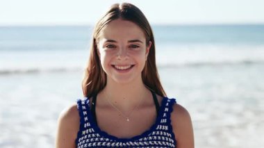 Camara 'nın önünde denizin önünde duran gülümseyen kızın videosu.