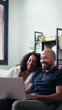 Evdeki kanepede otururken bilgisayar kullanan mutlu çiftin videosu..