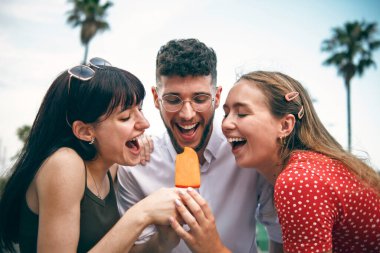 Yazın şehri gezerken elinde dondurmayla gezen komik arkadaşların fotoğrafı.