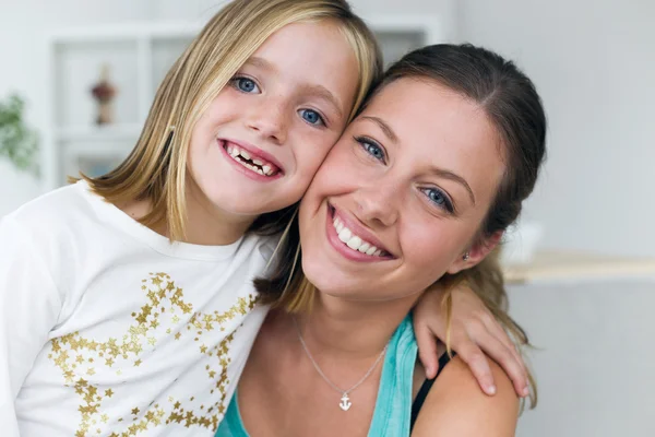 Junge Mutter und Tochter schauen zu Hause in die Kamera. — Stockfoto