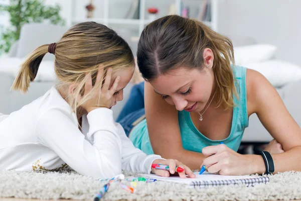 Genç anne ve kızı üstünde belgili tanımlık defter evde çizim. — Stok fotoğraf