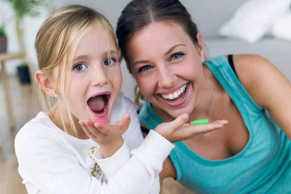 Junge Mutter und Tochter essen Süßigkeiten zu Hause. — Stockfoto