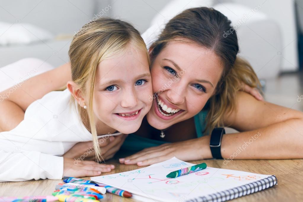 Young mother and daughter drawing on the notebook at home.