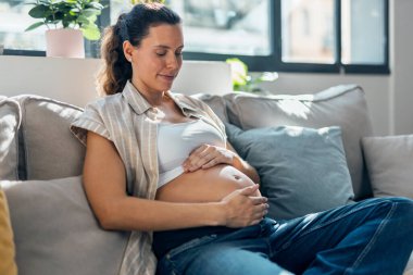 Hamile bir kadının karnına dokunup bebeğin hareketlerini hissettiği bir fotoğraf.