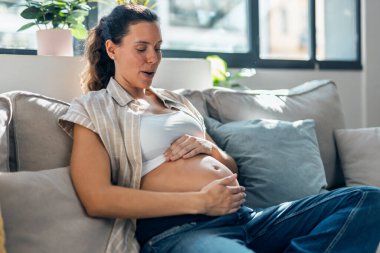Hamile bir kadının karnına dokunup bebeğin hareketlerini hissettiği bir fotoğraf.