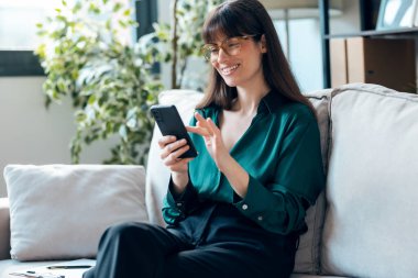 Ofisindeki kanepede otururken akıllı telefon kullanan kadın psikolog.