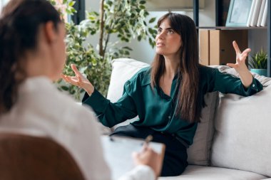 Psikolog not alıp psikoloji ofisinde kanepede otururken güzel bir kadının terapi görmesi.