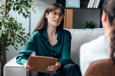 Psikolog bir hastaya terapi uygularken, psikoloji ofisinde kanepede otururken.