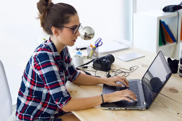 Młoda kobieta działa w jej biurze z laptopa. — Zdjęcie stockowe