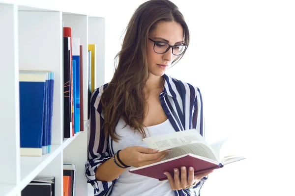 Piękna młoda kobieta czytanie w bibliotece. — Zdjęcie stockowe