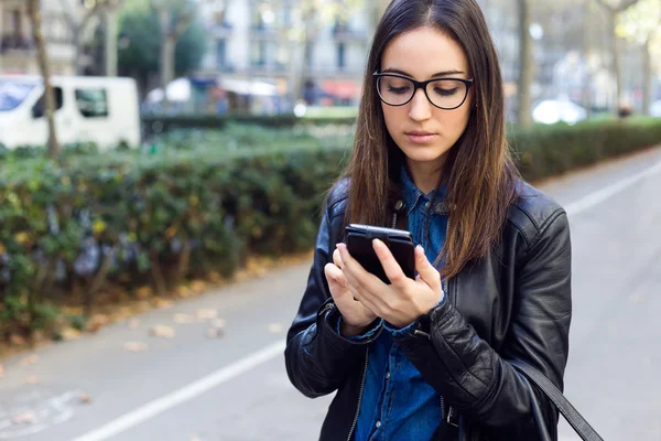 Mooie jonge vrouw met behulp van haar mobiele telefoon in de straat. — Stockfoto