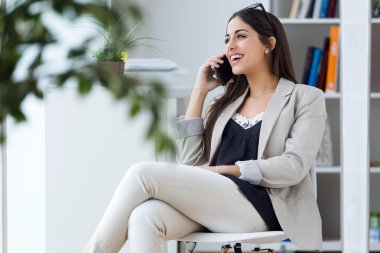 Ofiste cep telefonu kullanan genç ve güzel kadın.