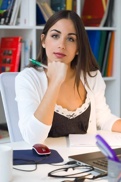 Mooie jonge vrouw die werkt met laptop in haar kantoor. — Stockfoto