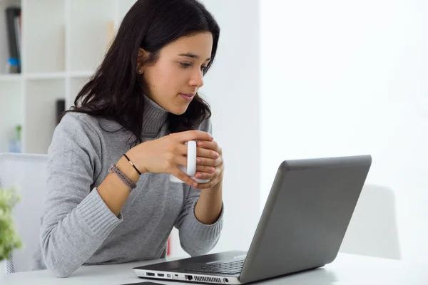 Vacker ung kvinna använder sin bärbara dator hemma. — Stockfoto