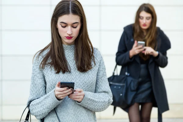 Two young businesswoman using mobile phone in the street. — Stock Photo, Image