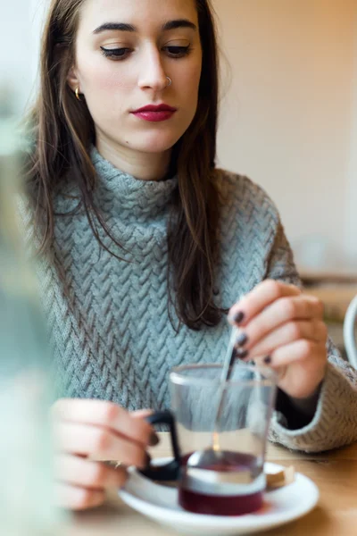 Hermosa joven bebiendo té en una cafetería . — Foto de Stock