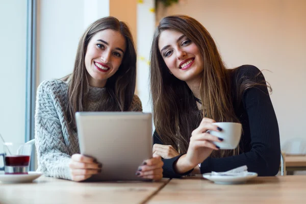 Mooie jonge vrouwen met behulp van digitale tablet in koffie winkel. — Stockfoto