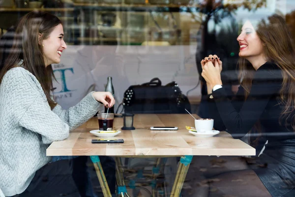 Hermosas mujeres jóvenes tomando té en una cafetería . — Foto de Stock