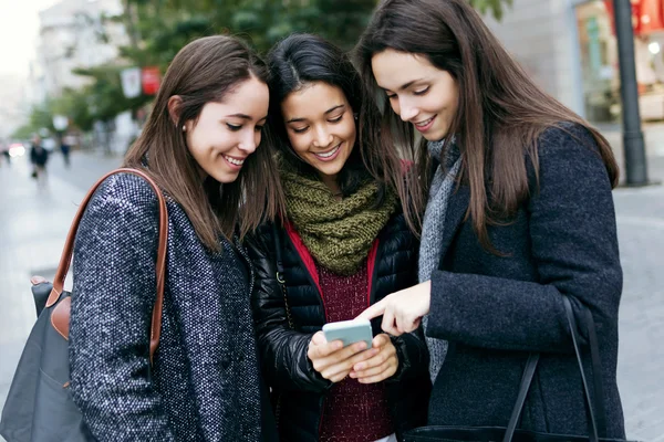 Porträtt av tre unga vackra kvinnor med mobiltelefon. — Stockfoto