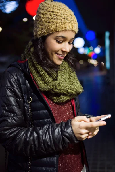 Портрет красивої молодої жінки, яка використовує свій мобільний телефон вночі — стокове фото
