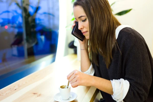 Vacker ung kvinna med hennes mobiltelefon på café butik. — Stockfoto