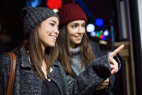 夜のお店のウィンドウを見て二人の若い美しい女性. — ストック写真