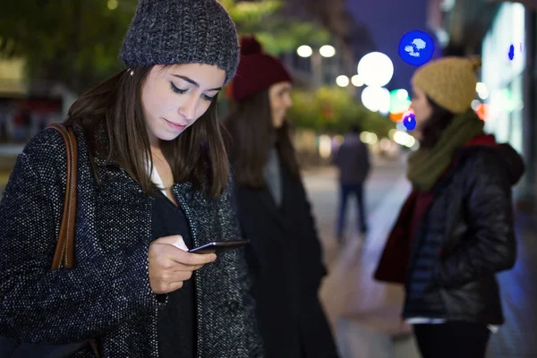 Porträt einer schönen jungen Frau, die nachts ihr Handy benutzt — Stockfoto