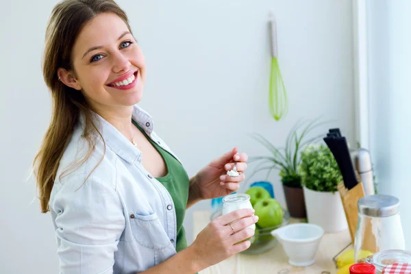Красивая молодая женщина ест йогурт на кухне . — стоковое фото