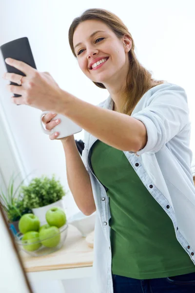 Bella giovane donna che utilizza il suo telefono cellulare e godersi la colazione — Foto Stock