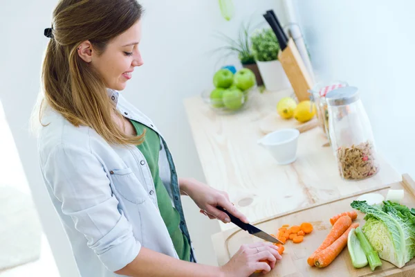 Mulher bonita cortando legumes na cozinha . — Fotografia de Stock