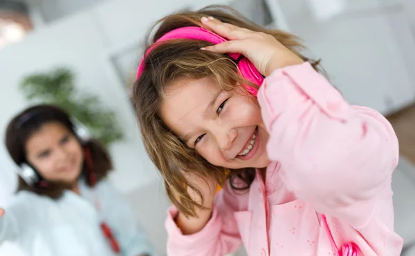 Two young sisters listening to music and dancing at home. — Stock Photo, Image