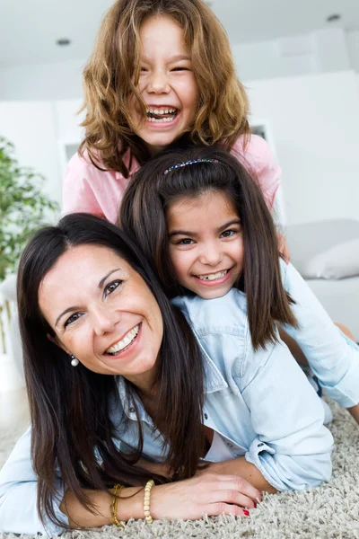 Bella madre con le sue figlie guardando la fotocamera a casa . — Foto Stock